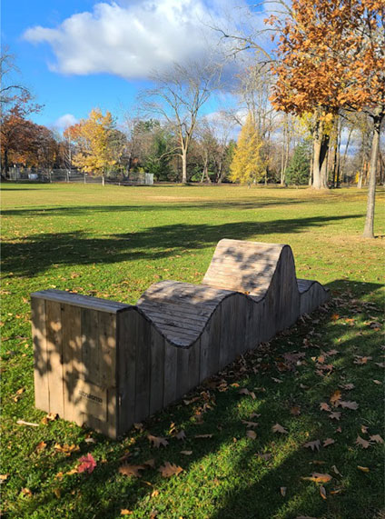 Banc public en bois brut formant une vague naturelle