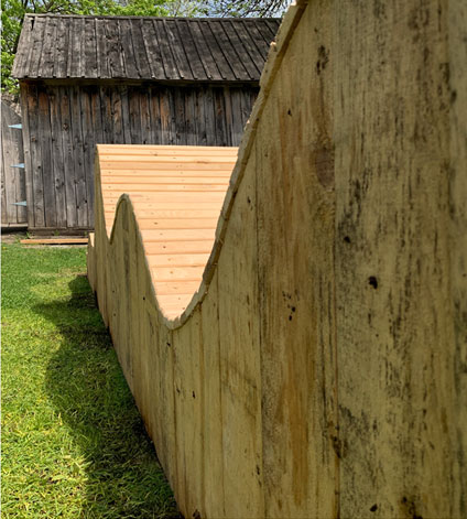 Structure sculpturale ondulée en bois brut intégrée à une terrasse extérieure