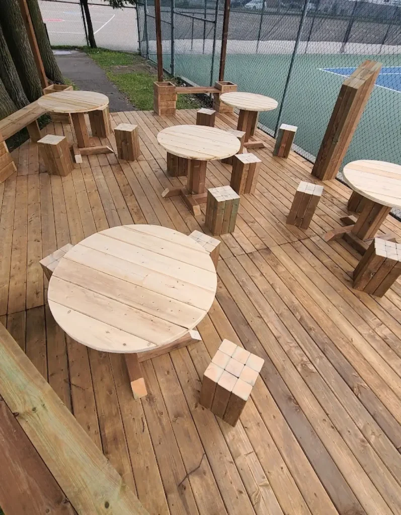 Assemblage de tables rondes en bois brut sur terrasse en cours d'aménagement