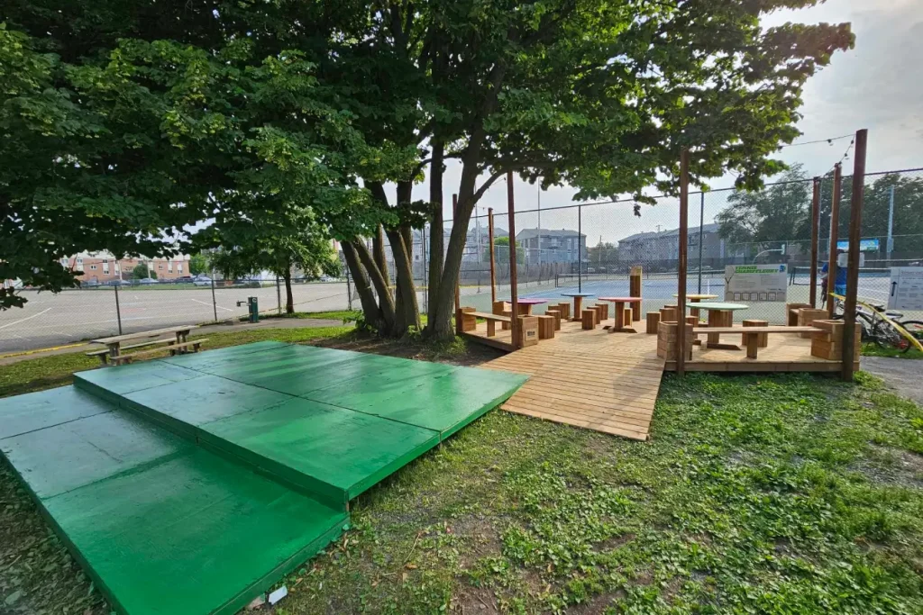 Terrasse en bois aménagée autour d'un grand arbre avec espace de repos