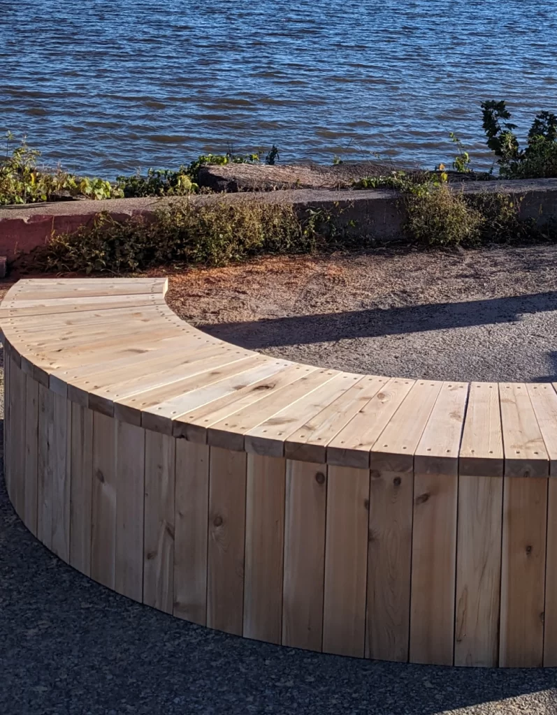 Banc demi‑cercle en bois installé au bord de l’eau à Saint‑Sulpice.