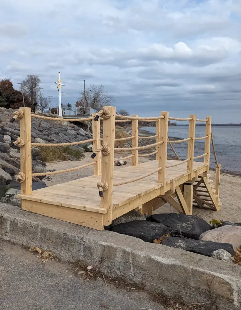 Plateforme en bois et rambarde nautique en corde sur le rivage.