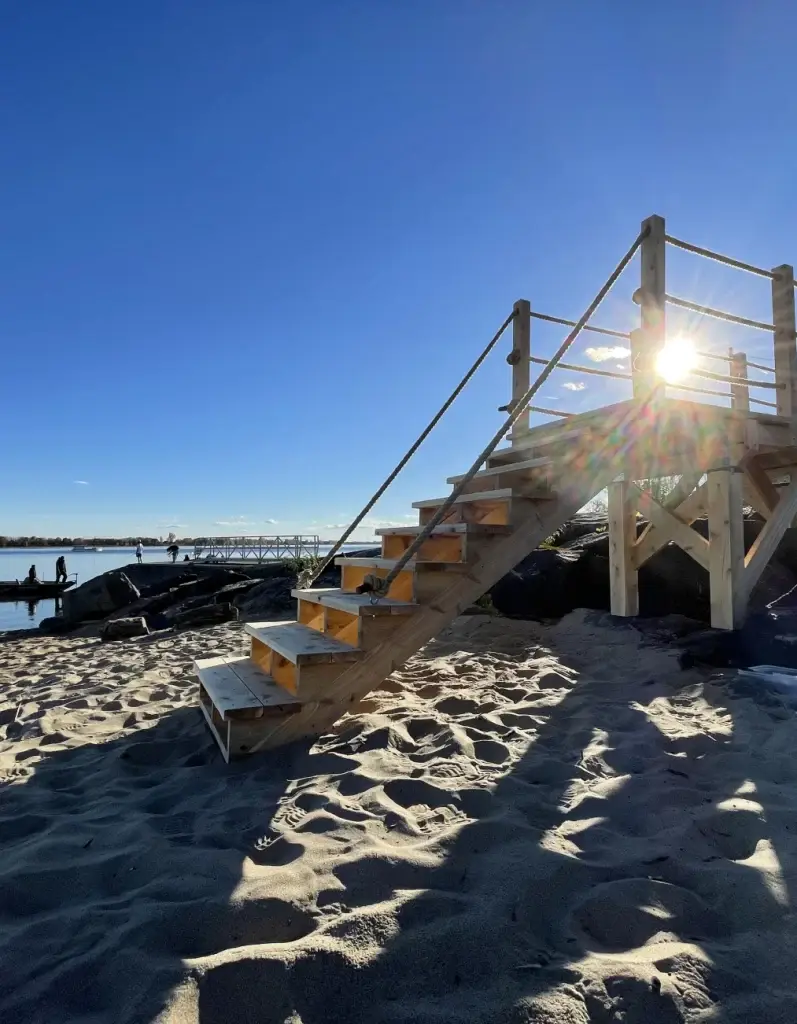 Escalier bois plage Saint‑Sulpice baigné de soleil, accès au fleuve.
