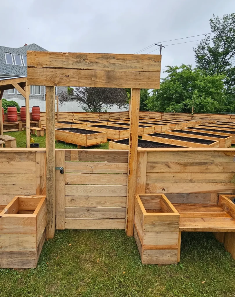 Portail d'entrée en bois brut encadré de bacs de jardinage