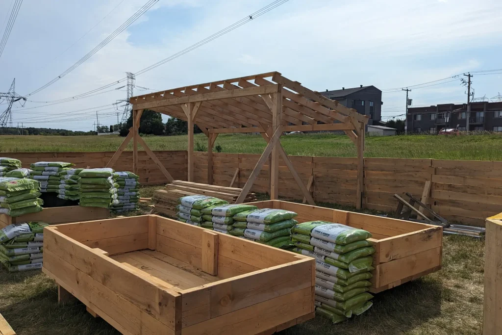 Alignement de bacs de culture et sacs de terre noire dans un jardin communautaire