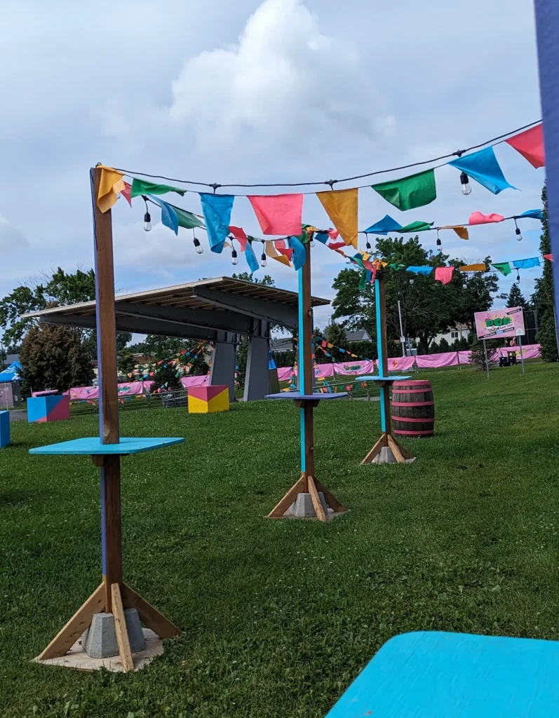 Tables hautes et fanions sous ciel bleu créant allée conviviale, festival POP ton été Terrebonne