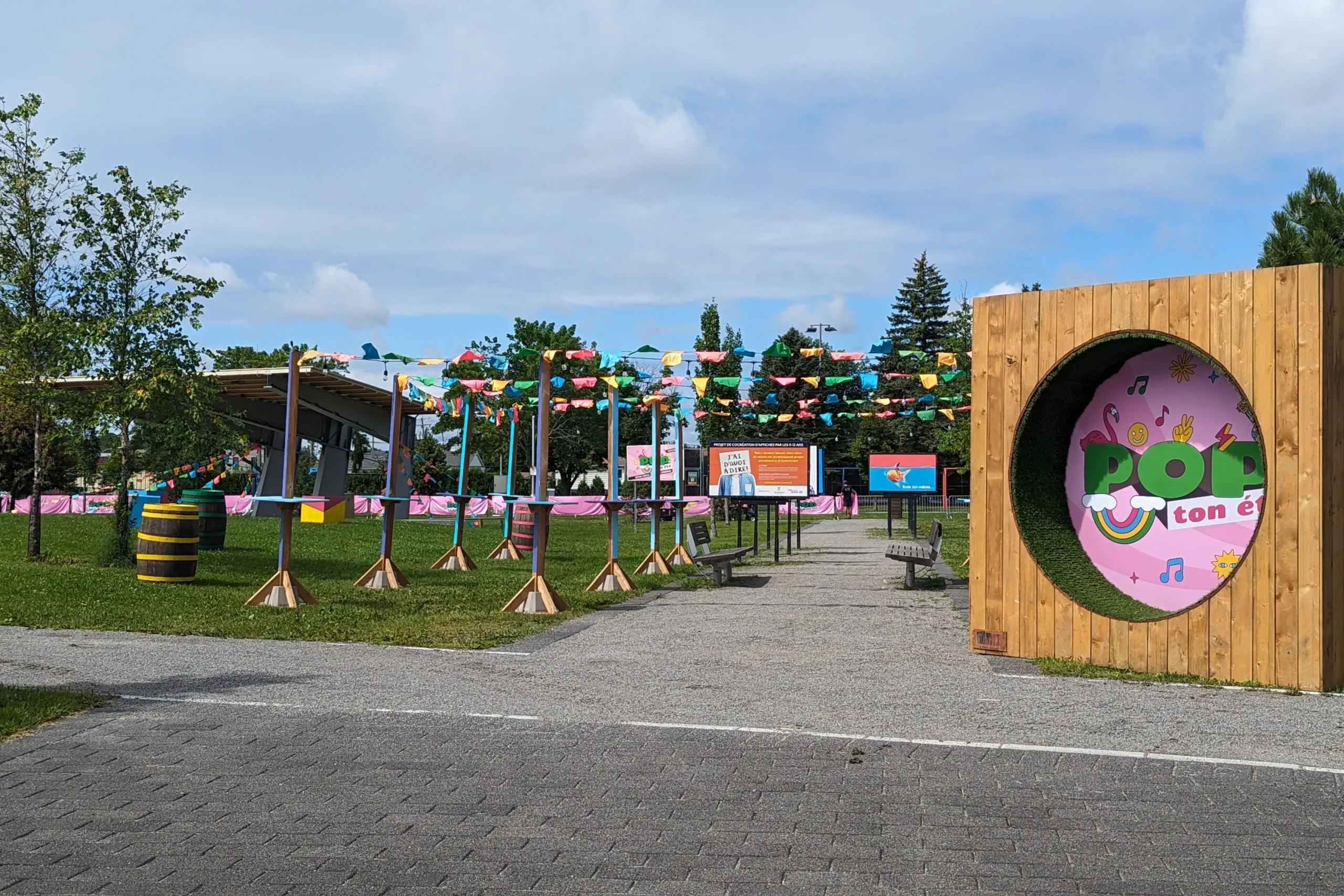 Entrée du site POP ton été avec arche bois et fanions, vue générale du festival à Terrebonne