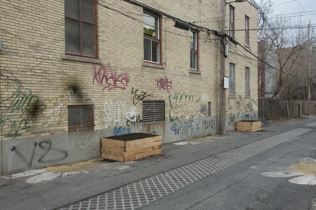 Bacs de jardinage en bois installés dans une ruelle urbaine graffitée à Montréal