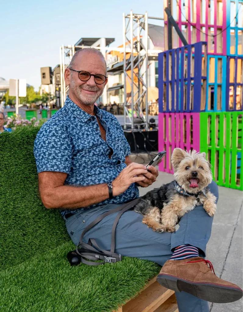 Festivalier assis sur banc en gazon avec petit chien, Centropolis, Laval