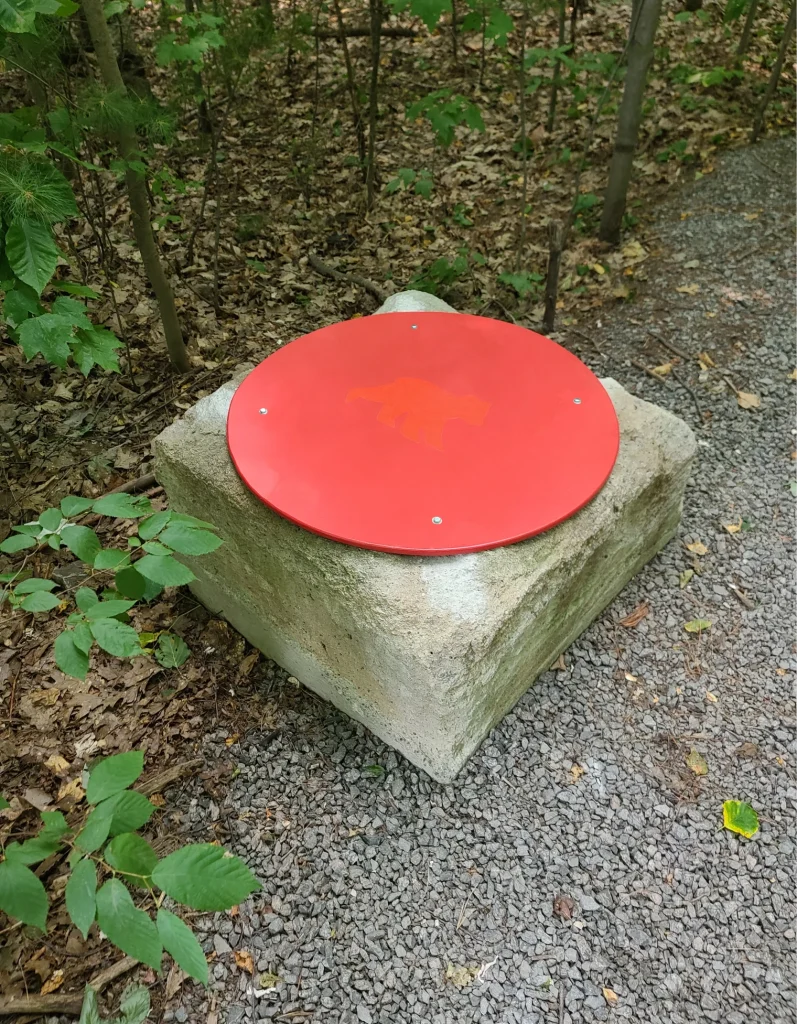 Balise ronde rouge fixée sur socle de béton le long du sentier