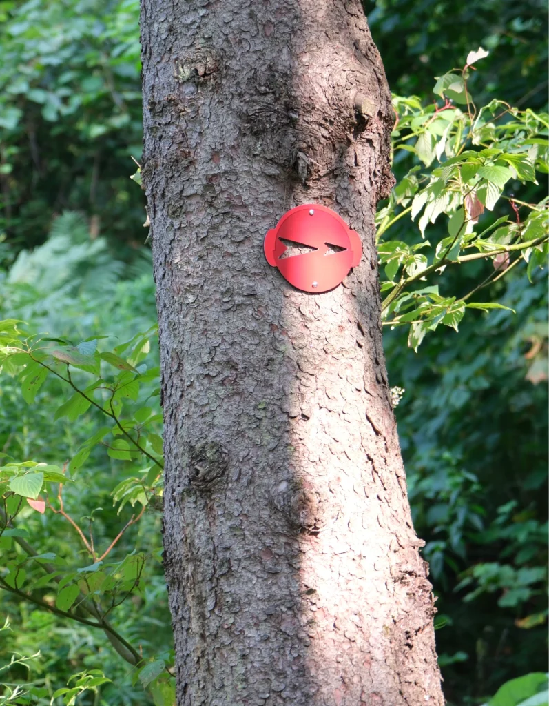 Plaque rouge découpée fixée à un arbre, repère du parcours