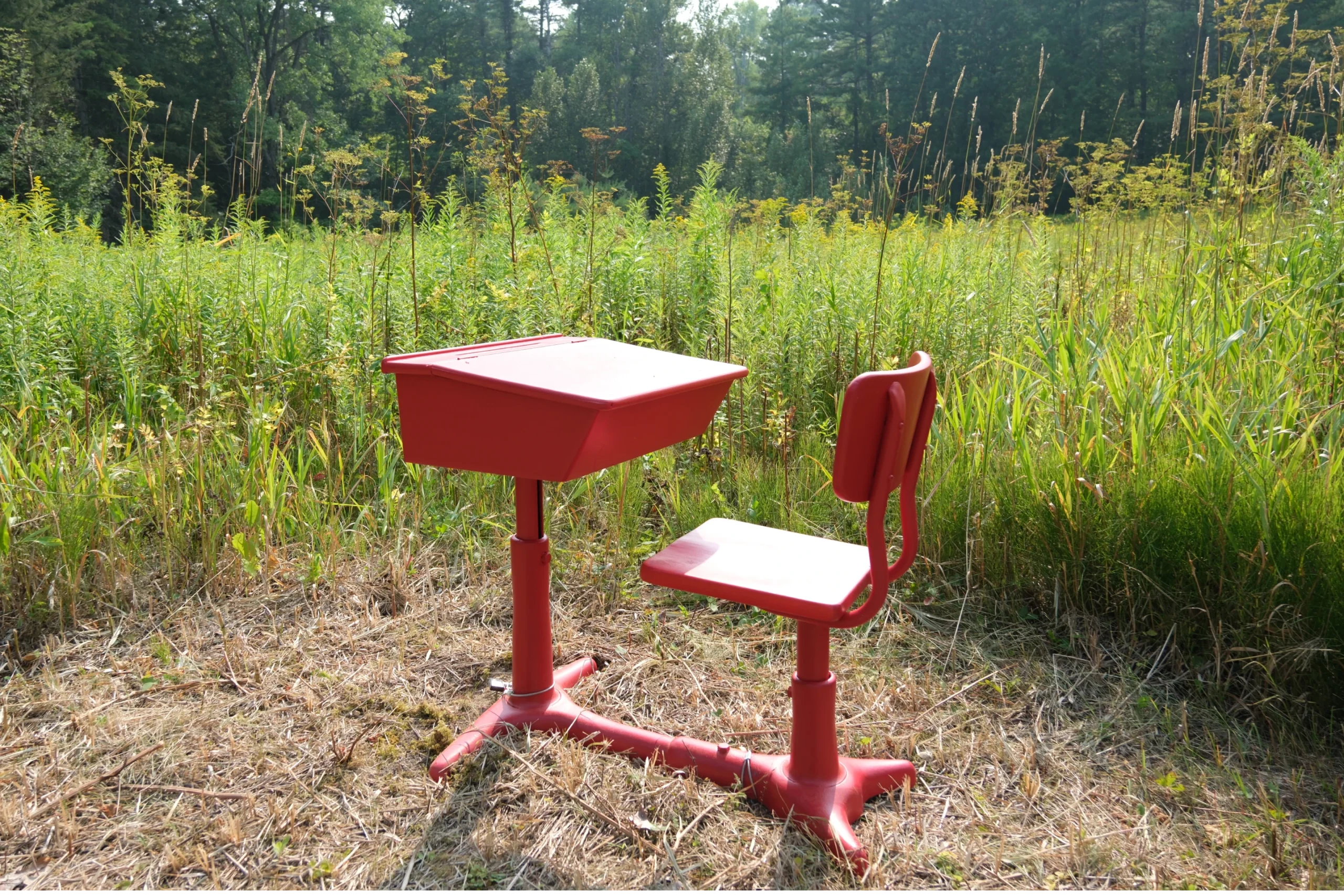 Pupitre d’écolier rouge posé en lisière de forêt à Mascouche