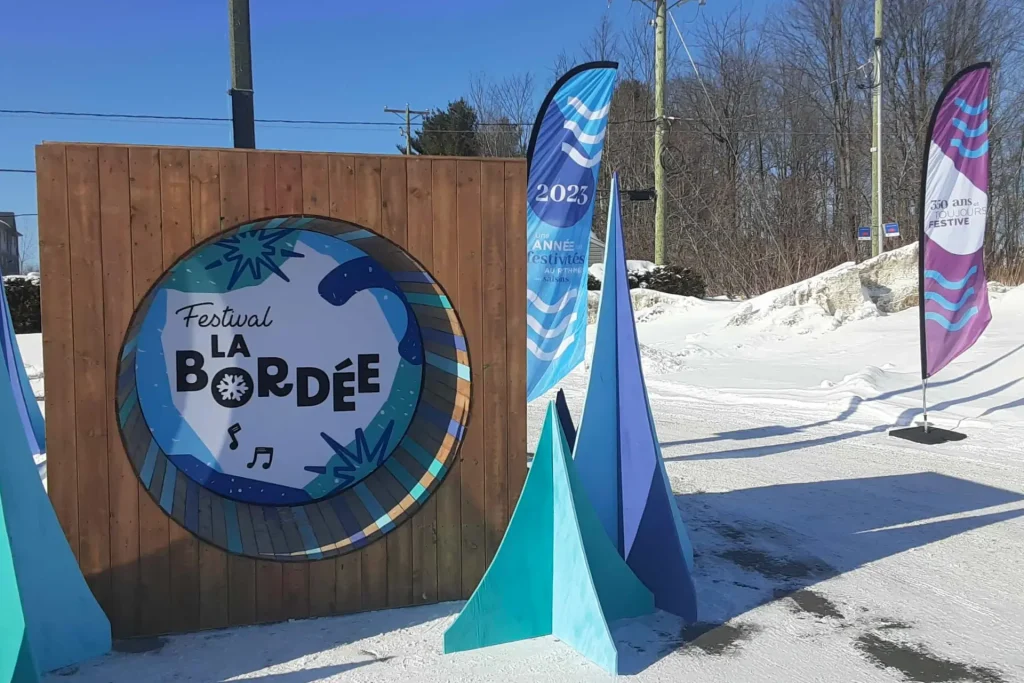 Mur d’entrée en bois avec hublot « La Bordée », fanions et neige, décor conçu et installé par Altruisma à Terrebonne.