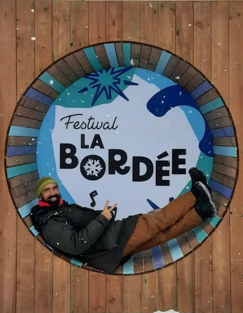 Visiteur posé dans la roue « La Bordée » sous la neige, décor événementiel conçu par Altruisma.