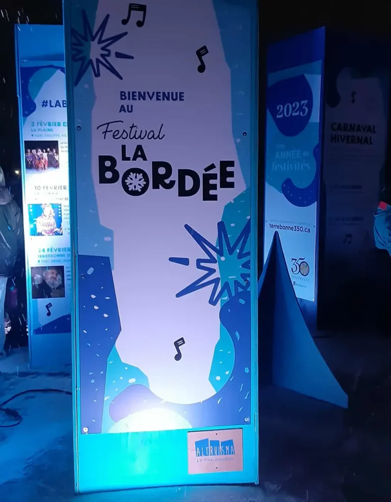 Colonne signalétique rétroéclairée « Bienvenue » de La Bordée, finition réfléchissante, de nuit à Terrebonne.