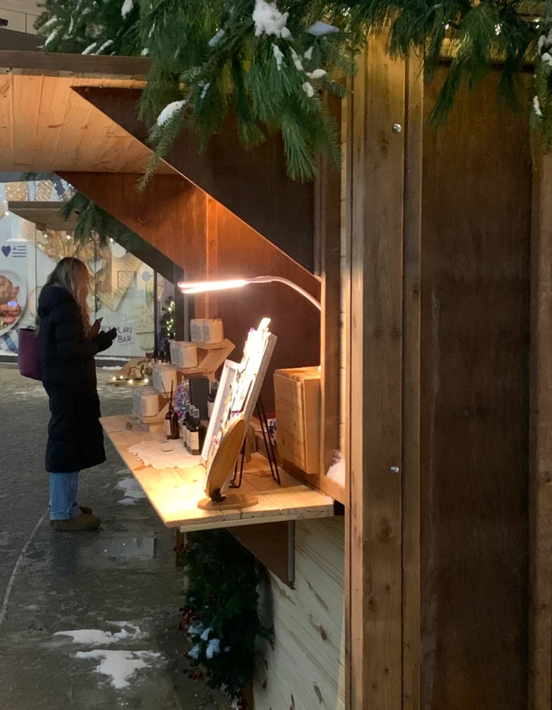 Détail du comptoir et de l’éclairage sous les conifères d’une maisonnette du marché.