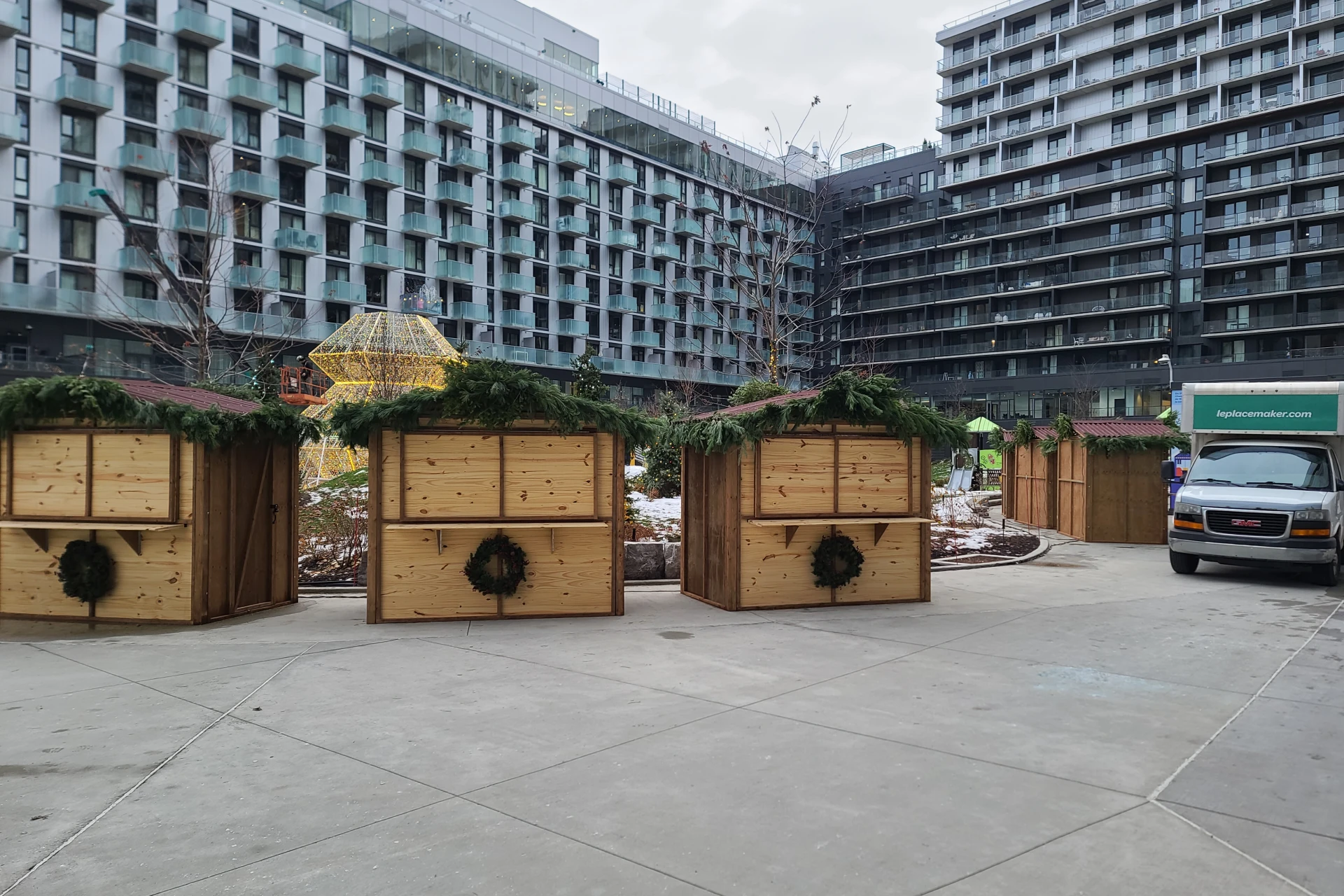 Rangée de maisonnettes en bois décorées de conifères au Marché de Noël d’Espace Montmorency, Laval.