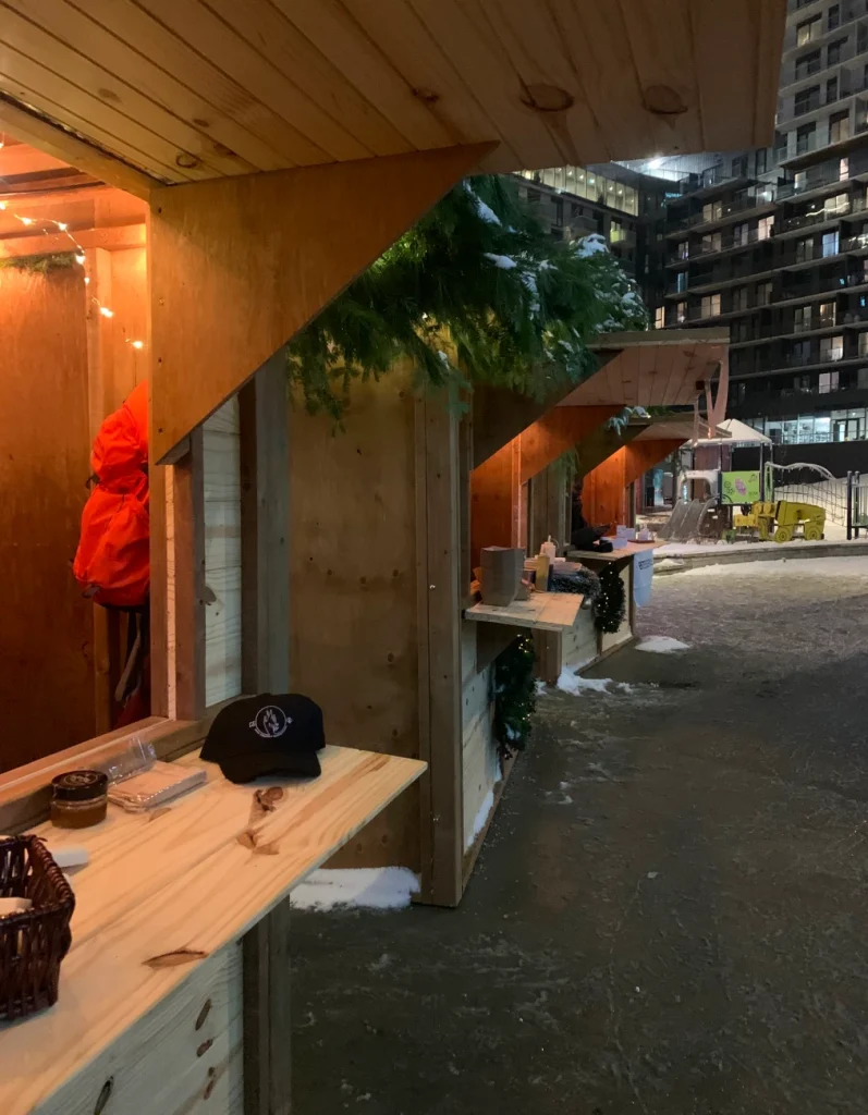 Maisonnettes animées en soirée, guirlandes et visiteurs au Marché de Noël de Laval.