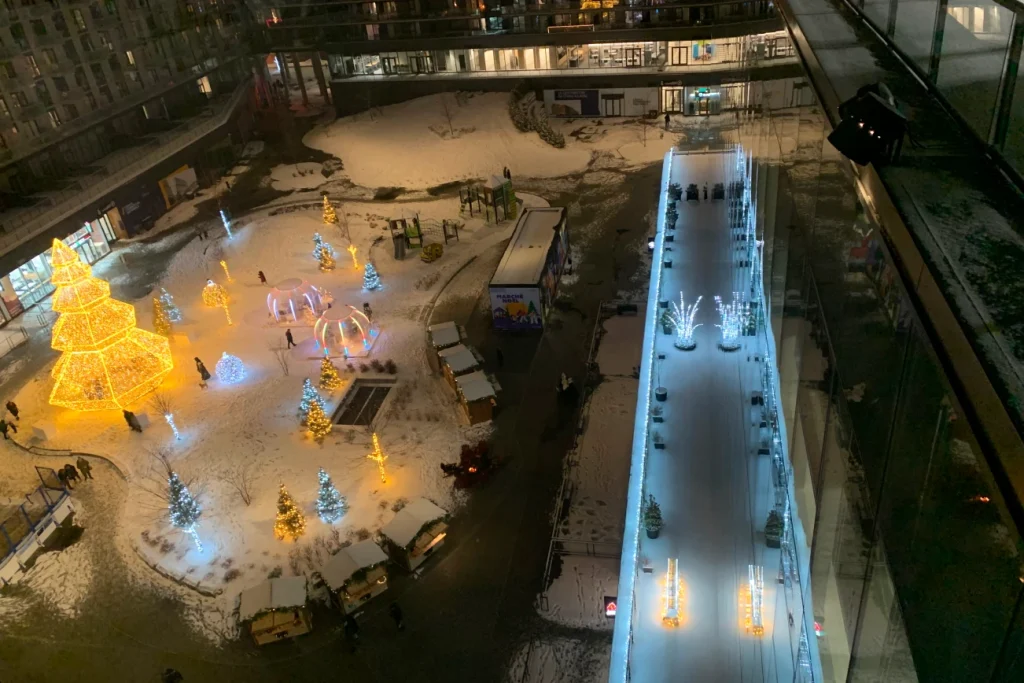 Vue aérienne nocturne du Marché de Noël à Espace Montmorency, chalets et décor lumineux.